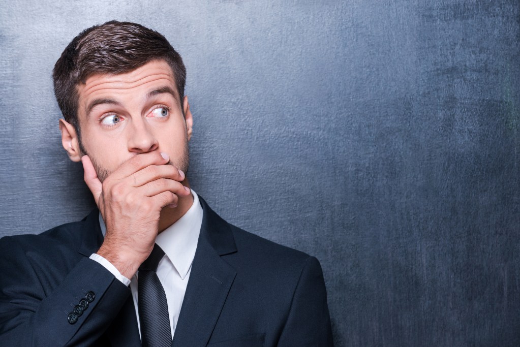 Embarrassed young man covers his mouth concerned about his oral health. Bad breath, gum disease, oral cancer, cavities, bleeding gums, dental hygiene, dental hygienist, dental cleanings, gum care, oral health.