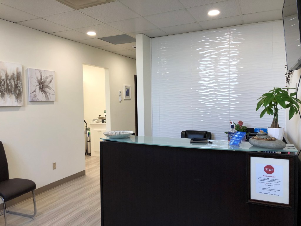 Brown desk and wave feature wall inside reception area at Word of Mouth Dental Hygiene. Oshawa dental hygienist Wendy Horler, clean office, professional, relaxing, dental cleanings, oral health.